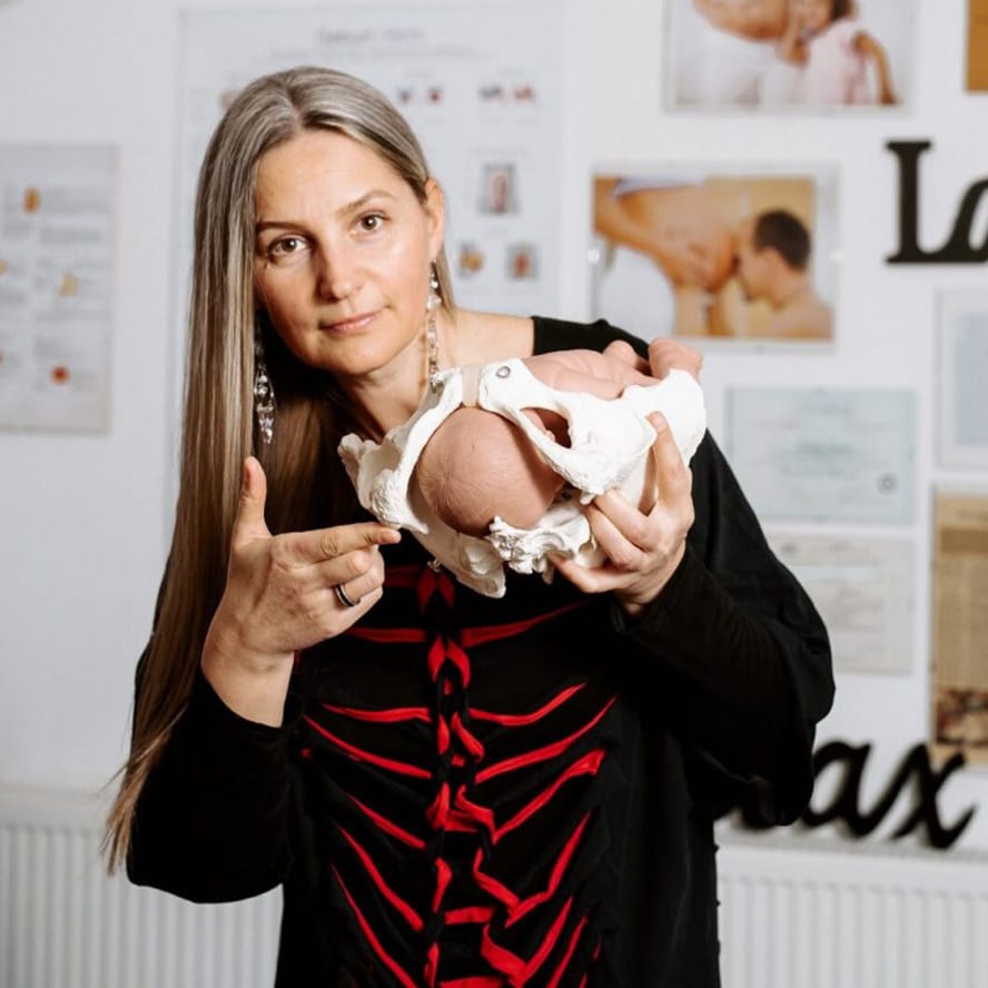 Ditta Depner explicând mecanica nașterii cu un model anatomic de bazin și un bebeluș